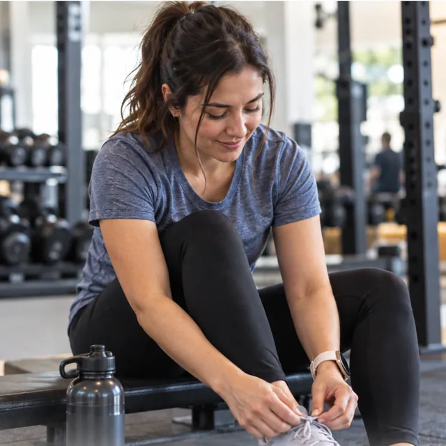 Mujer amarrándose las zapatillas antes de empezar a entrenar en el gimnasio